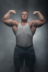 Powerful muscular bodybuilder posing on a black background. concept of strength and health