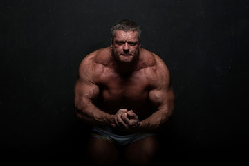 Fototapeta na wymiar muscular man shows off his body near black grunge wall