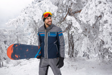 young male snowboarder with snowboard on winter holiday in the mountain