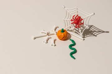 Composition of plastic toys for Halloween, with pumpkin, spider, cobweb, snake and bones