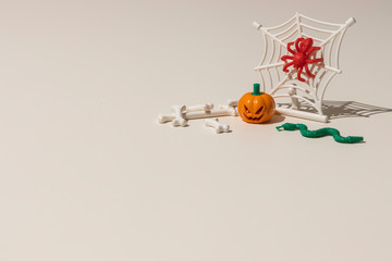Composition of plastic toys for Halloween, with pumpkin, spider, cobweb, snake and bones