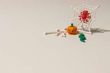 Composition of plastic toys for Halloween, with pumpkin, spider, cobweb, snake and bones