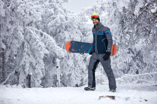 young man with ski mask holding his snowboard, extreme sport and winter holiday
