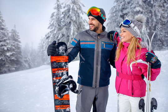 smiling couple skiing and snowboarding enjoying in snowy mountains together
