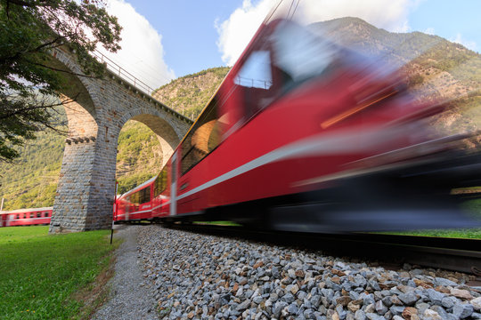 Train passing under the Brusio Spiral Viaduct in UNESCO landscape along the Bernina Railway Line. Val Poschiavo, Graubuenden, Switzerland.