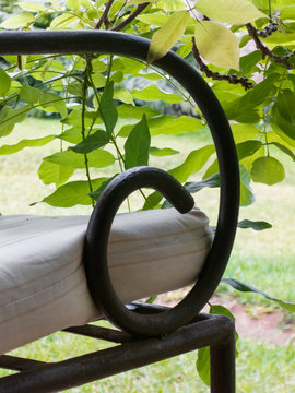 Armrest of a metal chair with a cushion and leaves in the garden