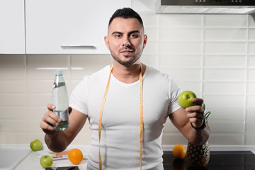 male nutritionist keeps a bottle of water and an apple in the kitchen