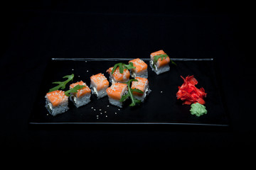Sushi roll with salmon and avocado on plate on black background top view