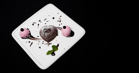 Dessert fondan chocolate with ice-cream on a white plate on a black background. Exquisite French chocolate dessert fondan, place for text