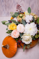 Autumn floral bouquet in a pumpkin vase on a light background, a mixture of flowers, pionic rose, eucalyptus, chrysanthemum
