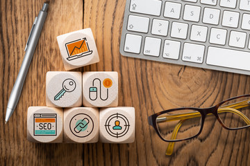 Online-Marketing Komponenten als Symbole auf Würfeln am Arbeitsplatz