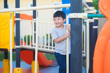 Asian kid playing at the playground under the sunlight in summer, Happy kid in kindergarten or preschool school yard.