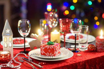 Beautiful table setting for Christmas party or New Year celebration at home. Cozy room with a...