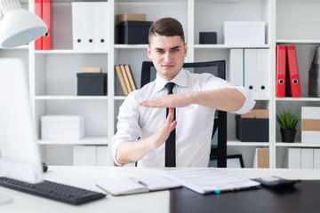 Fototapeta premium The young man is sitting at a computer Desk in the office and put his hands perpendicular to each other.