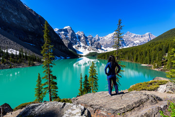 Woman on cliff admiring Moraine Lake and mountains scenic view, Rocky Mountains, Banff National...