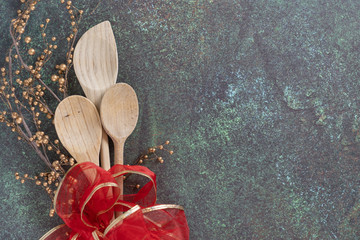 red ribbon with wooden spoons on blue green counter top from above for holiday baking concept