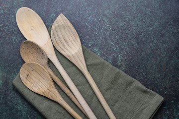 horizontal wooden spoons and green kitchen towel on blue green counter top