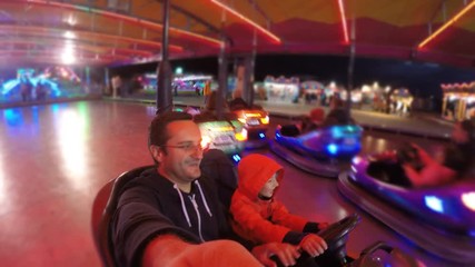 Child and father have fun at roller coaster, night amusement park