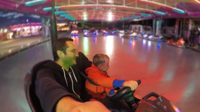 Confident child is driving  at roller coaster, father have fun with son 