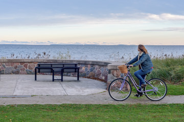 cheerful woman riding bike along Lake Superior shoreline in fall