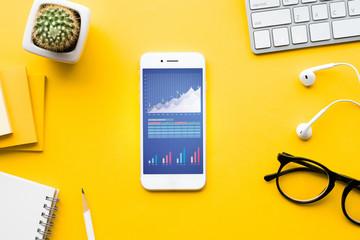 Top view of office desk table with graph chart on mock up smartphone