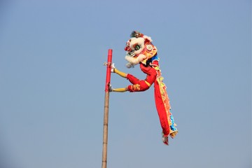 Chinese lion dance on the pole with the background of clear blue sky.