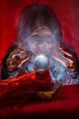A crystal ball lies between the hands of a fortune teller, fog rises