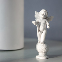 An angel statuette and a white violin on the table. Interior decoration