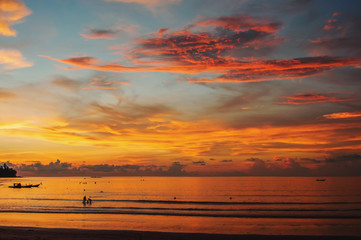 Beautiful scenery of the ocean at sunset with a wave on the shore and bizarre clouds