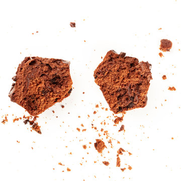 An overhead photo of a messy chocolate muffin, cut into halves, with crumbs, shot from above on a white background with a place for text