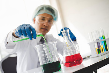 Scientific concept in laboratory - Scientist are pouring various color test tubes to analyze and...