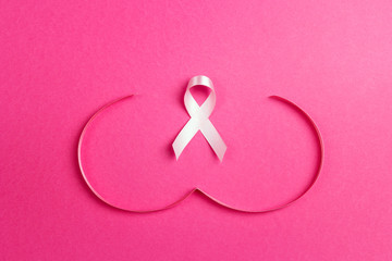 Pink ribbon with breast shape symbol on pink background. Breast cancer awareness symbol.