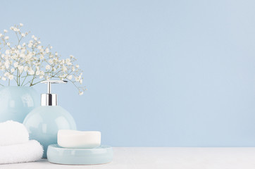 Bathroom interior - ceramic accessories - light blue circle vase with white flowers, soap dispenser , fluffy towels on white wood table.