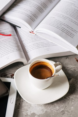 Group of opened books, cup of coffee, tablet and smartphone on a gray background, Overhead view.