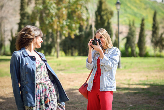 Two young tourist women taking photographs outdoors