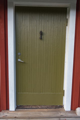 Obraz na płótnie Canvas green door on a little red cabin in sweden 