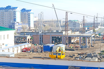 Construction site of a brick house. Truck cranes, workers and construction materials. 