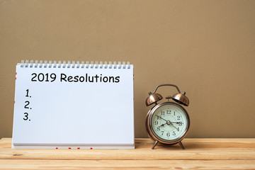 2019 Resolutions text on notebook and retro alarm clock  on table and copy space. Goals, Mission and New Start Concept