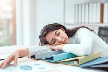Tired businesswoman sleeping with document on the desk at office. Overwork, working overtime and...