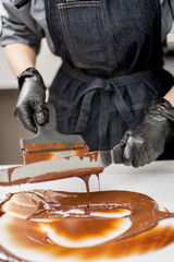 Pastry chef making hand made chocolate sweets wearing black gloves 