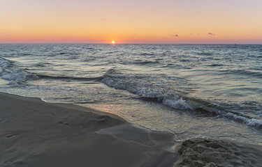 Sunset on Baltic Sea white pastel color sky and rough sea. 