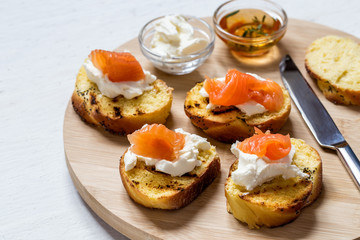 Sandwiches with fish salmon and cream cheese on a round Board on a light background