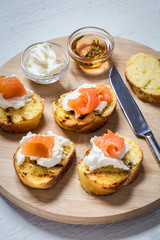 Sandwiches with fish salmon and cream cheese on a round Board on a light background