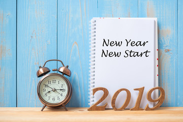 2019 Happy New year New Start Text on notebook, retro alarm clock and wooden number  on table and copy space. Resolution, Goals and Mission Concept