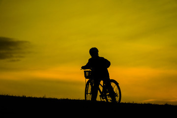 Fototapeta na wymiar 日没の丘で自転車に乗る少年