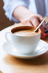 Close up of cup of coffee on a working table, woman holding her
