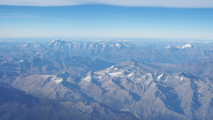 Fototapeta premium Flying over the European Alps during fall season. Landscape at the Mont Blanc and the glaciers. Aerial view from the airplane window