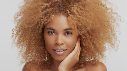 mixed race black blonde model with curly hair touching her face