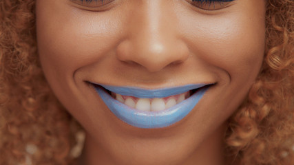 mixed race black blonde model with curly hair closeup of mouth painted with bright blue lipstick....