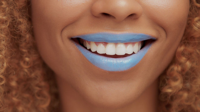 mixed race black blonde model with curly hair closeup of mouth painted with bright blue lipstick laughing mouth